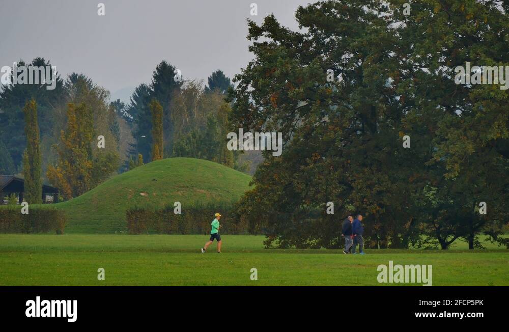 man with hat running in the park surpassing a couple under a bunch of