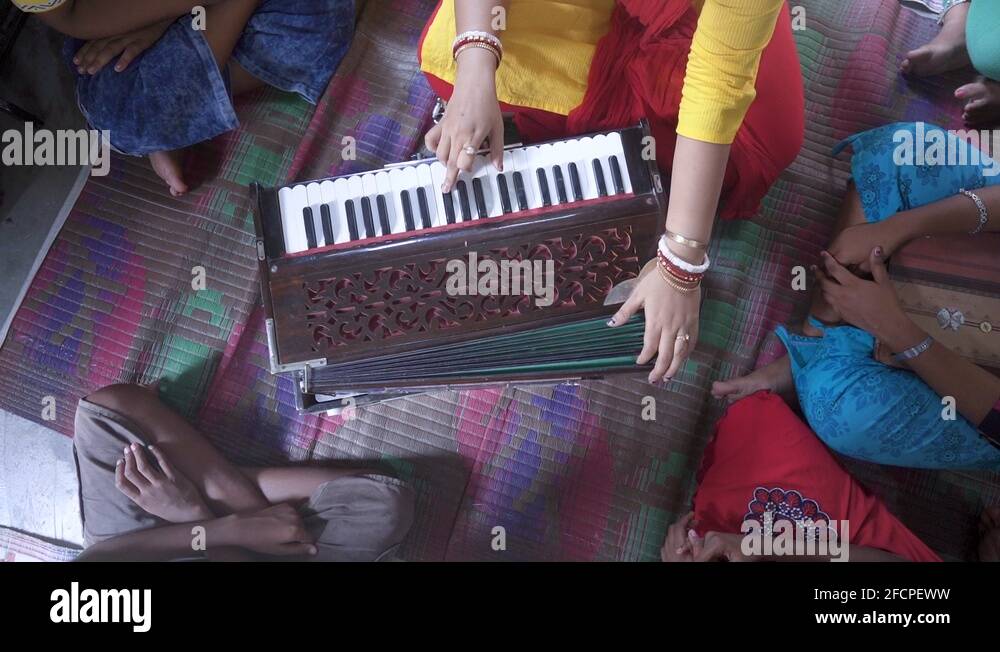 Married Indian teacher teaches music with harmonium at rural classroom