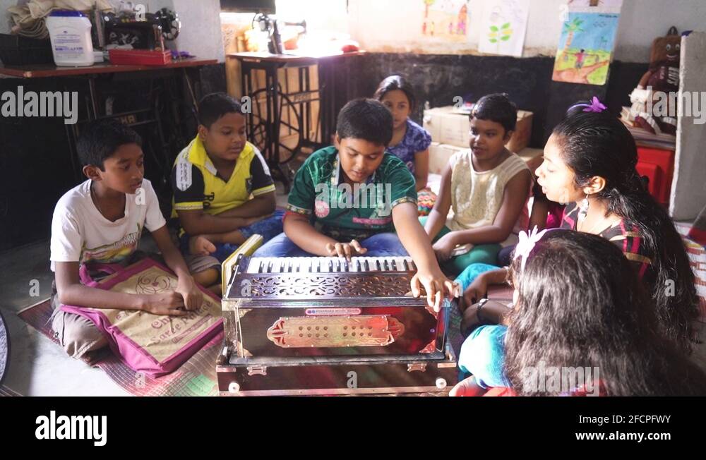Poor Asian children playing music with harmonium and singing at