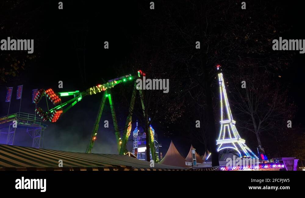 Funfair park illuminated swing carousel and eiffel tower at night,wide