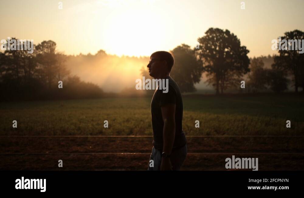 Silhouette male person having morning walk with foggy sunrise, lateral ...