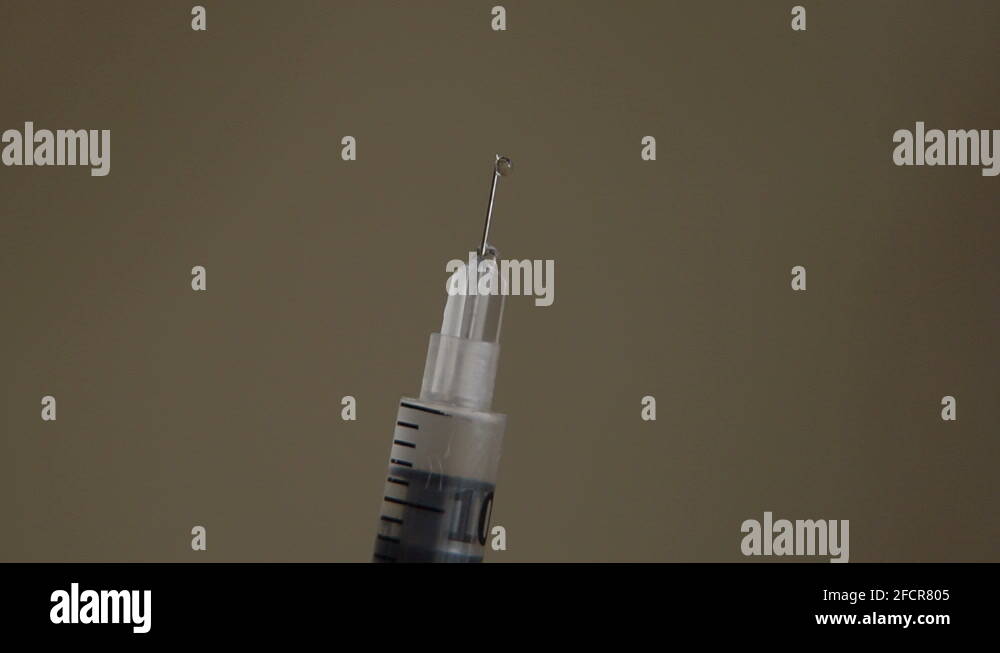 Closeup of insulin syringe with needle and drops the drugs on blurred