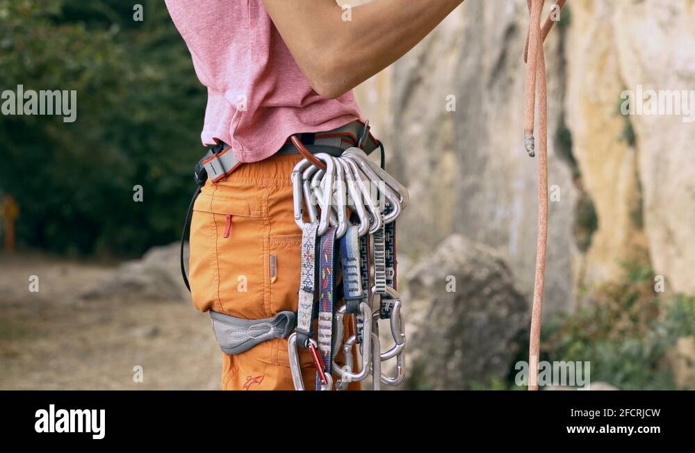 Rock climbing detail of climber harness with gear and hands grabbing