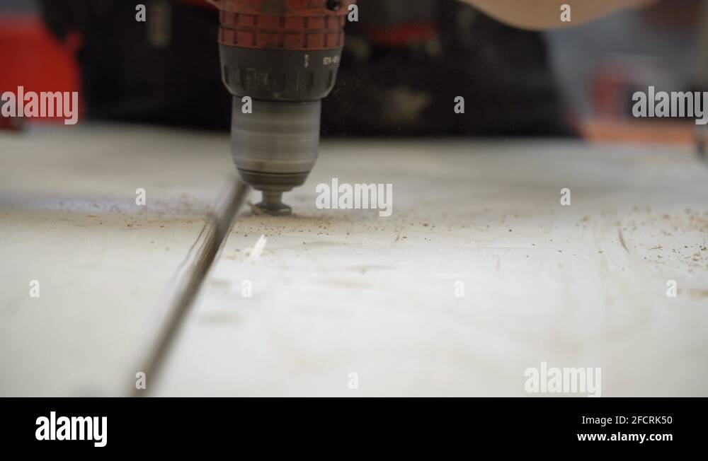 Drilling a round hole in the plywood element. Carpenter using drill