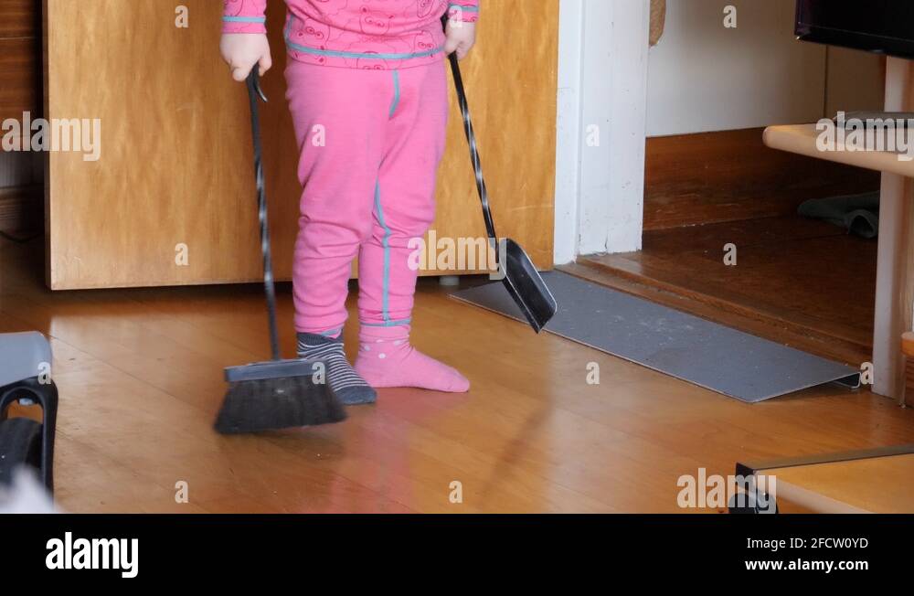 Adorable toddler mimics parents example and tries to sweep the floor