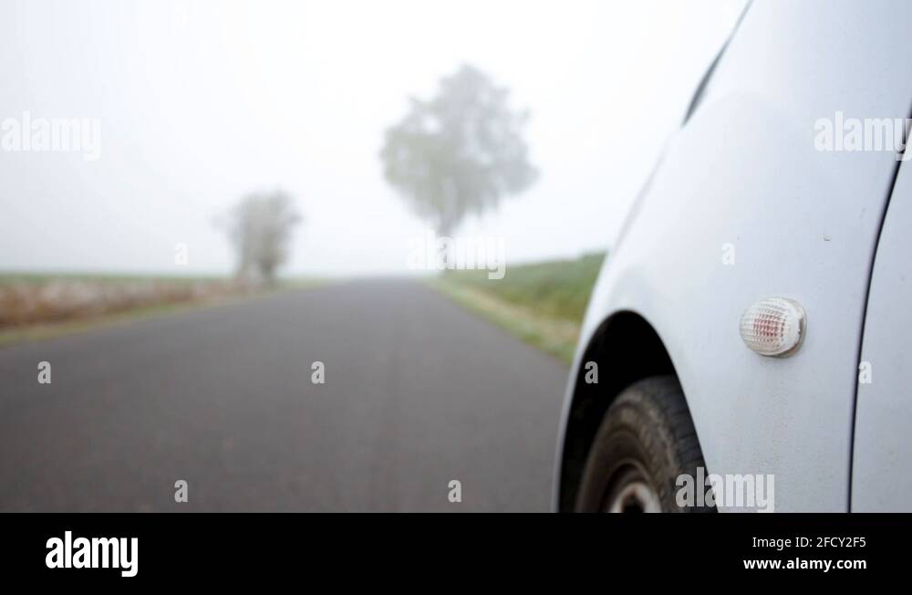 Car parked while orange hazard light is blinking on the road close up