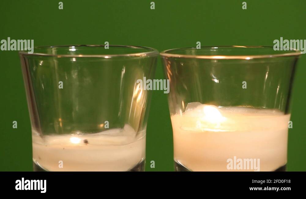 Glass white candles, two blow out causing smoke on green screen