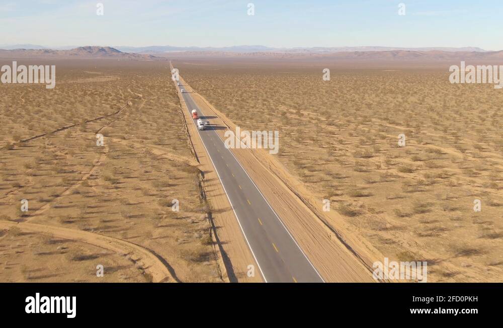AERIAL Freight trucks haul cargo down empty freeway crossing the Mojave desert Stock Video