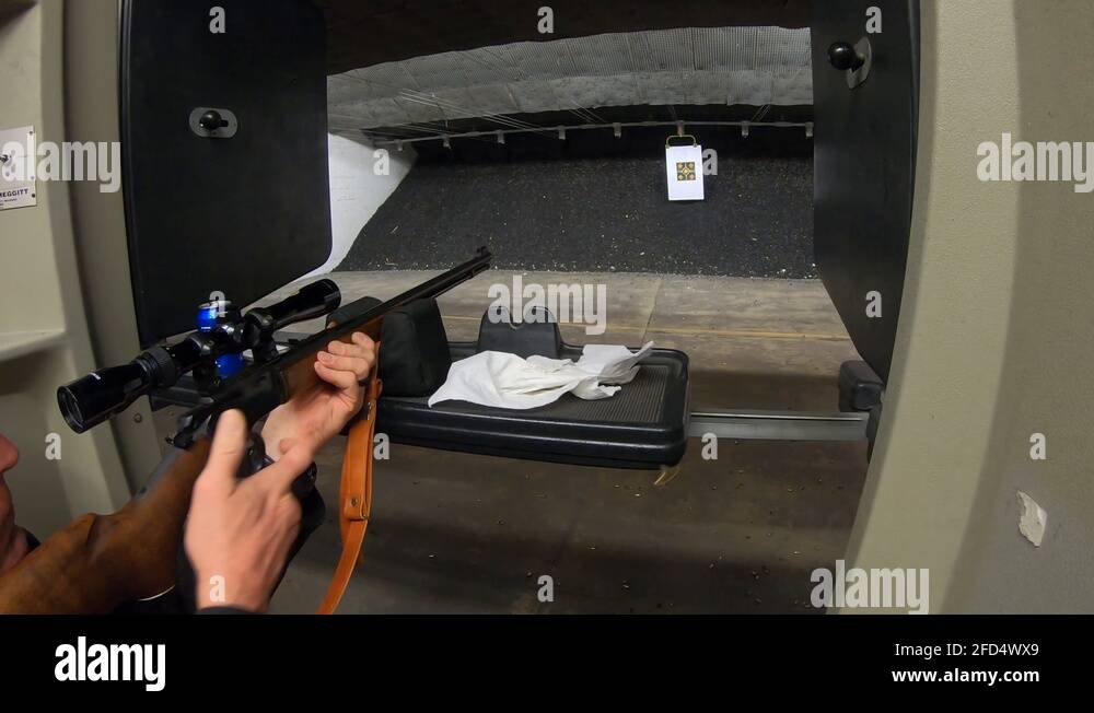 Man wearing safety glass shooting a rifle with an scope at paper target