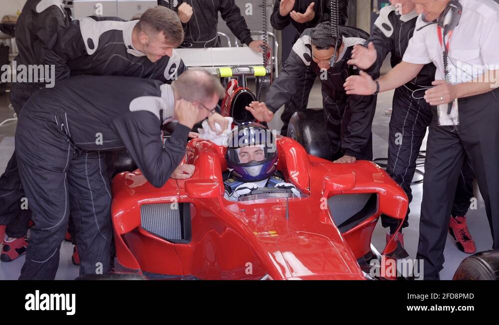 Racing team and male race car driver cheering and celebrating at race
