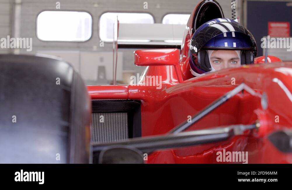 Serious, focused male race car driver wearing helmet in race car in ...