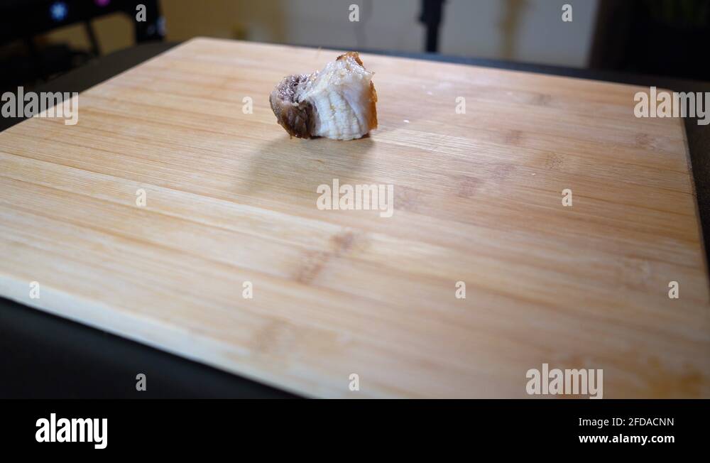 Placing pork fat and skin on chopping board. Newly cooked pork lechon
