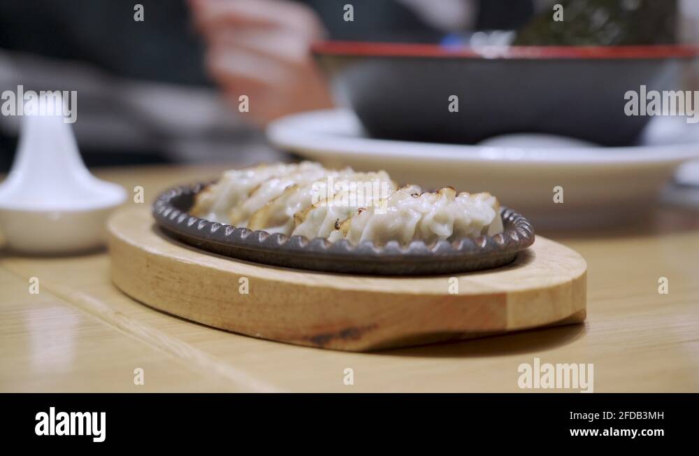 4k japanese fried gyoza on at local restaurant , wooden hot plate Stock