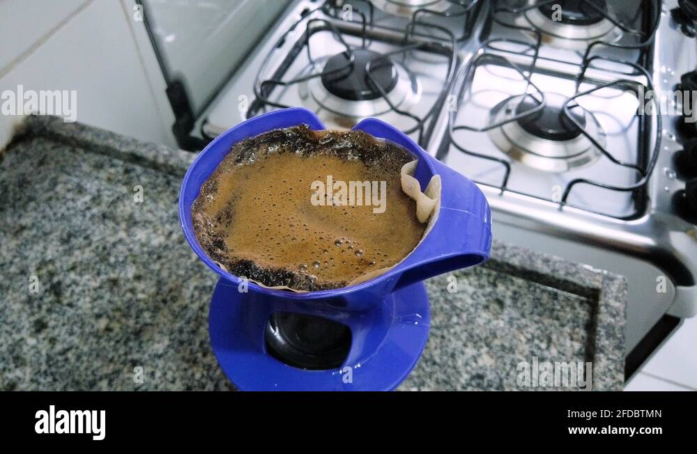 Strain coffee through the filter paper over the kitchen sink Stock