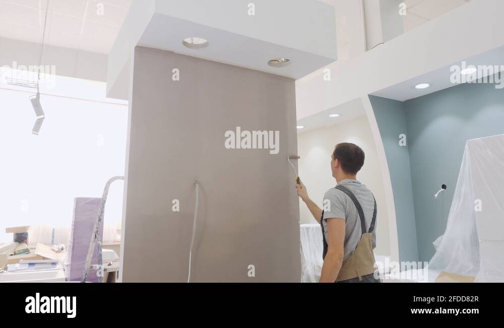 muscular painter in jumpsuit colours small wall in beige Stock Video Footage Alamy