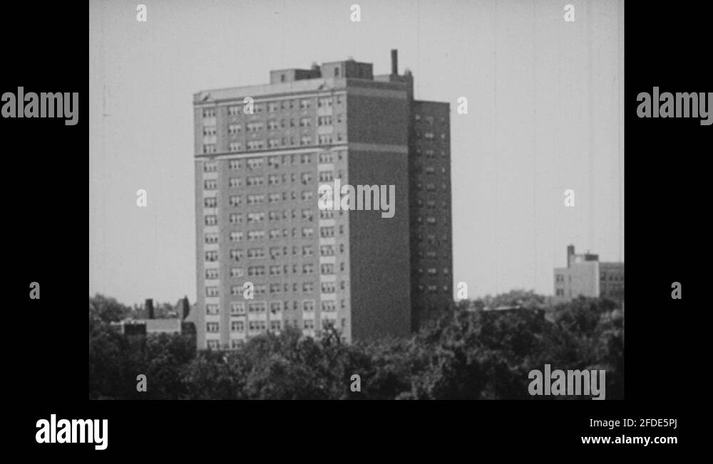 1950s: Apartment building among trees in city. City skyline above trees ...