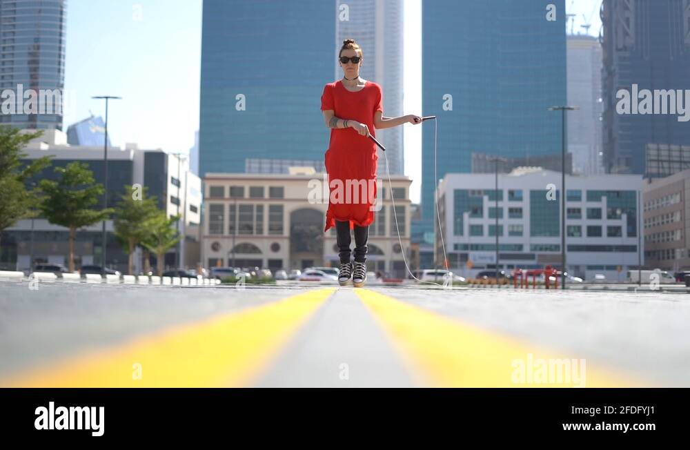 Young girl jumping with jump rope with cityscape background of Dubai in