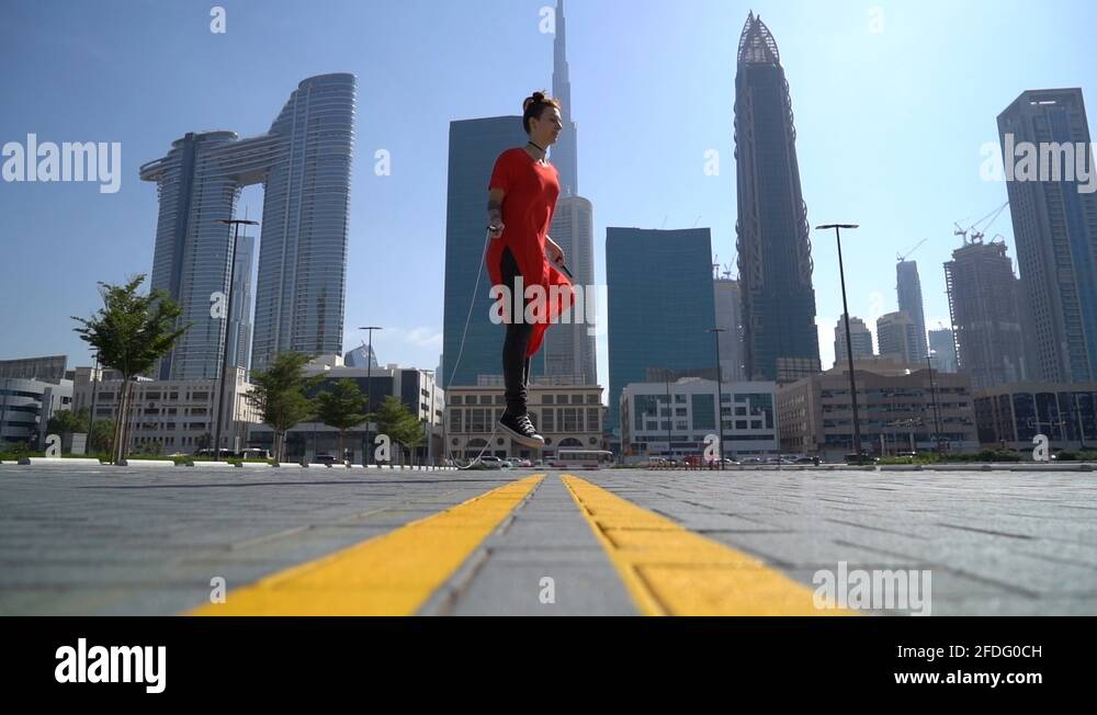 Young girl jumping with jump rope with cityscape background of Dubai in