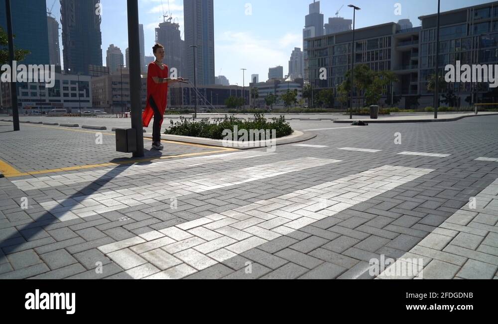 Young girl jumping by crosswalk with jump rope with urban background of