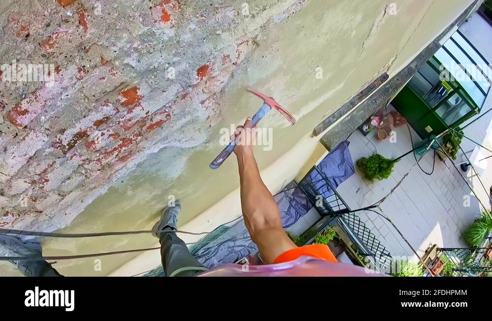 Abseiler working in construction repairs a damaged wall Stock Video