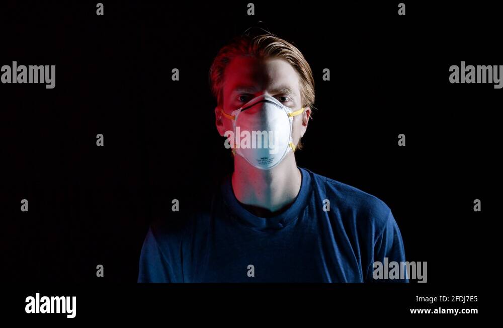 Young man coughing with medical mask dramatic lighting. Portrait of a