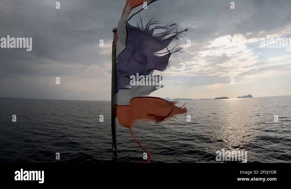 Torn Flag of Thailand on a boat flapping against the wind sailing off
