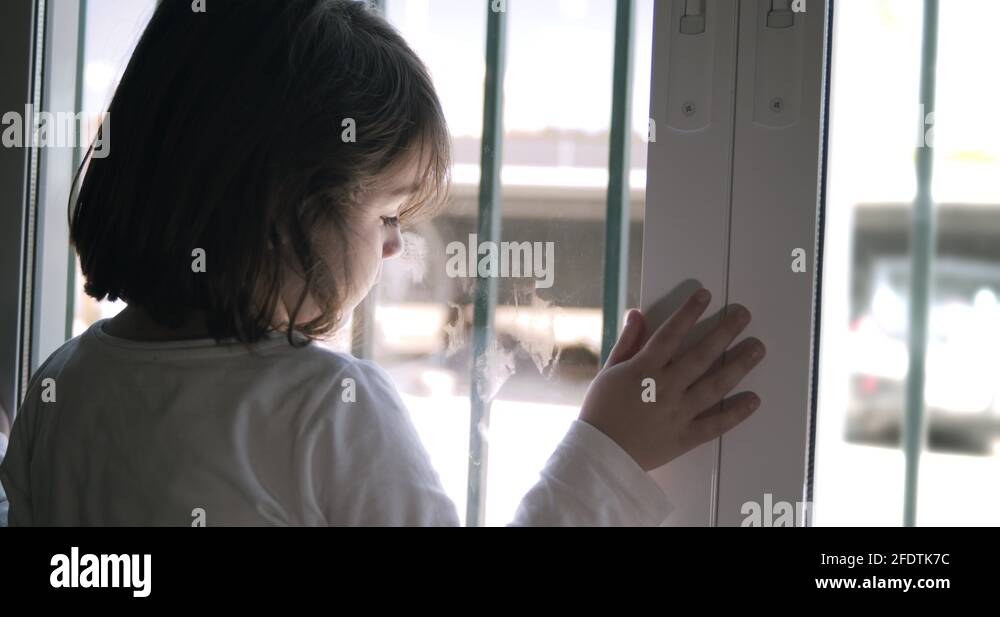 Little girl looking through the window during the confinement of the Stock Video Footage Alamy