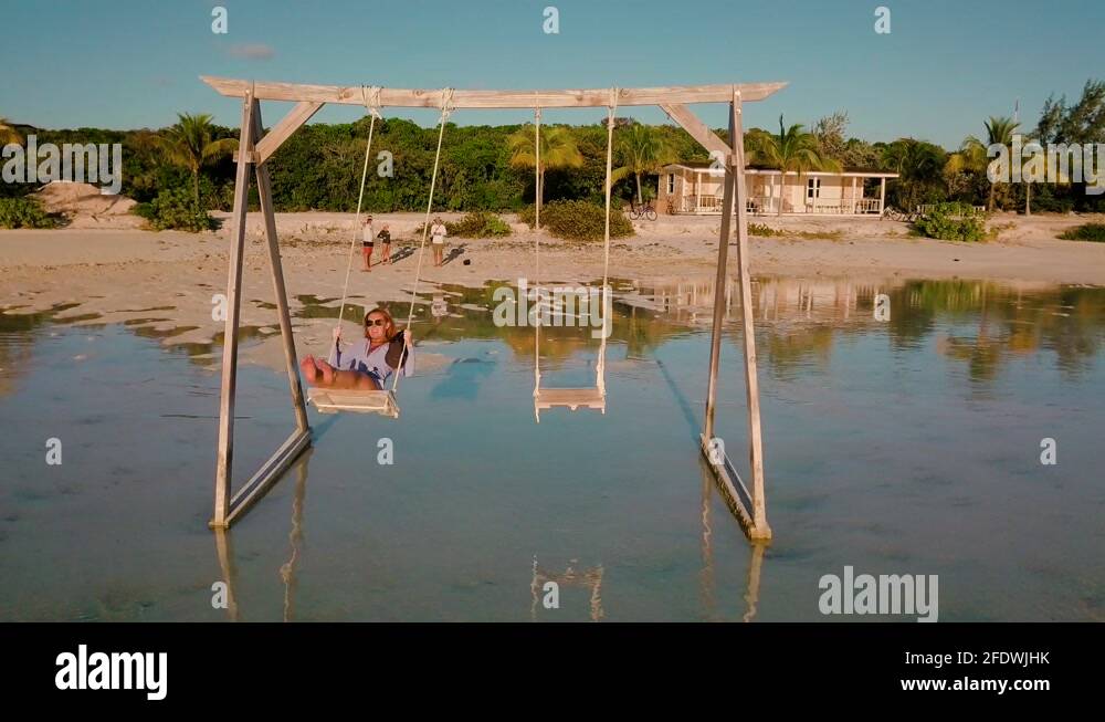 Girl swinging on instagrammable wooden swingset over ocean in the