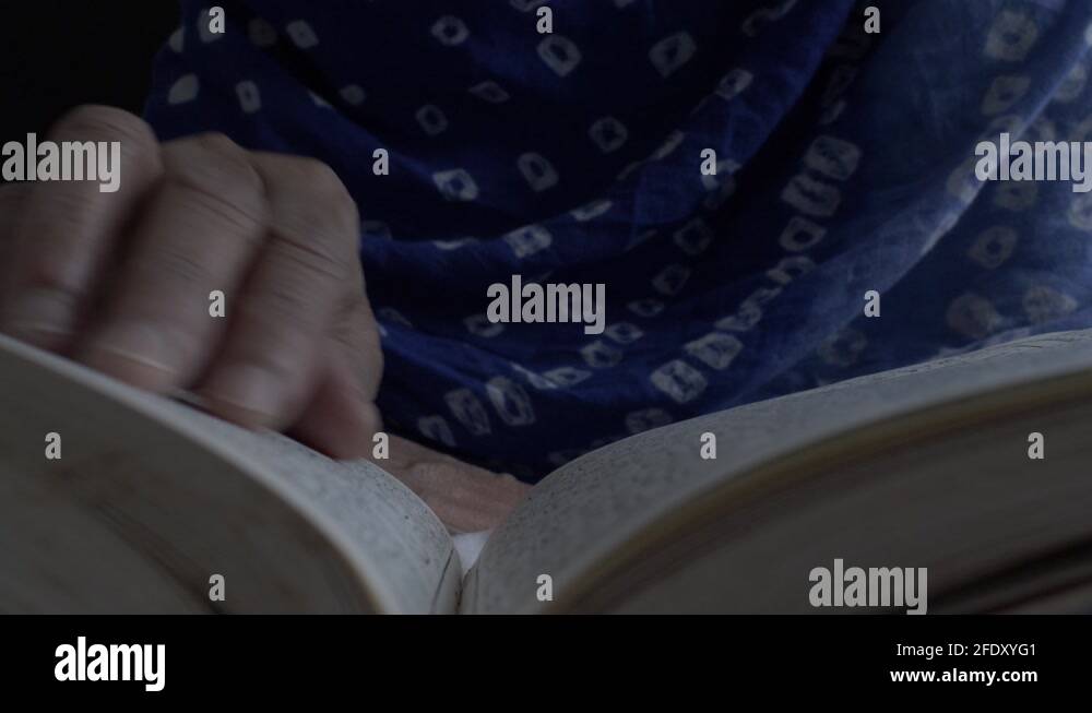 Muslim Women Sitting On Bed Reading Holy Quran. Low Angle, Close Up