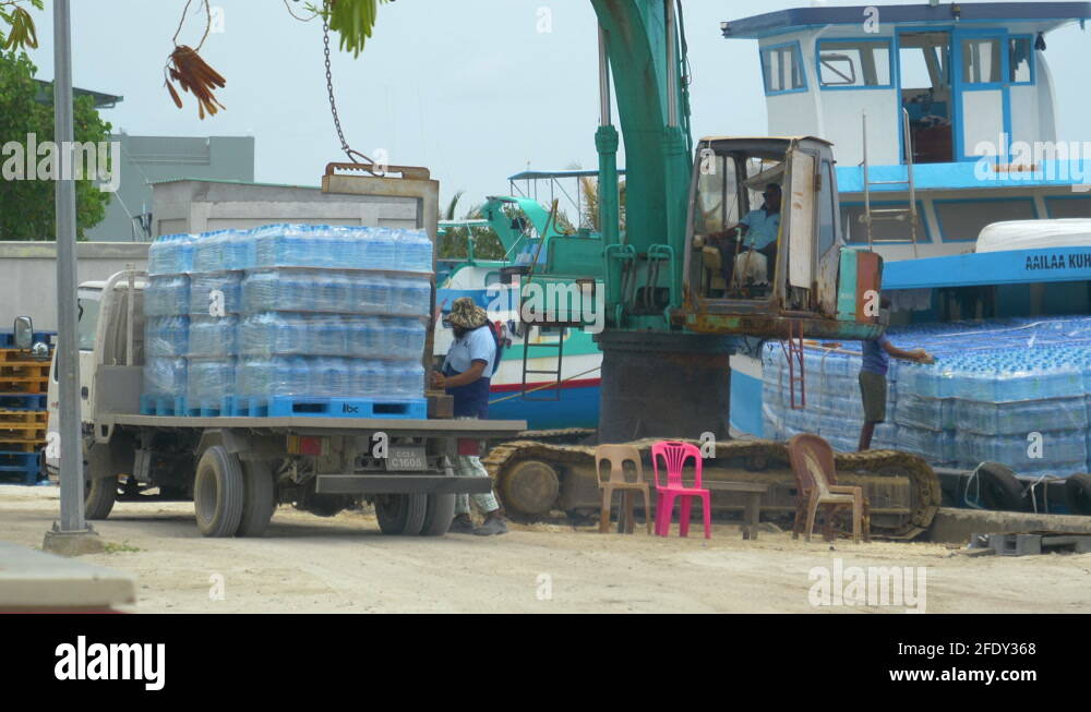 Locals transfer pallets full of water bottles from delivery truck to