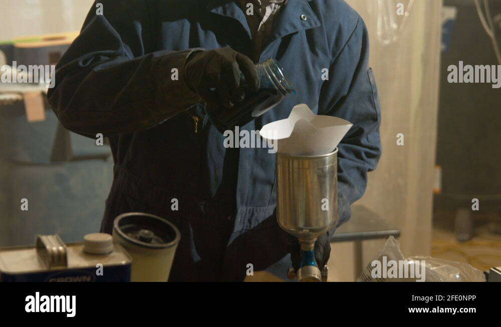 Dumping a mixture into a paint sprayer. To get it ready for painting