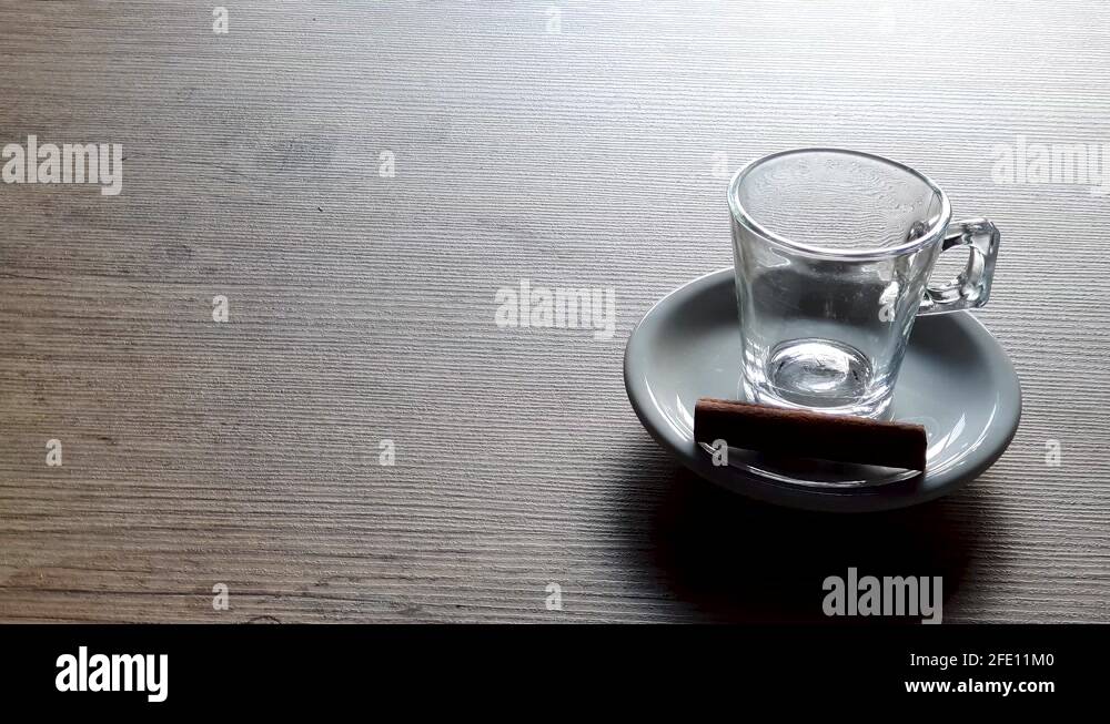 Pouring coffee in empty transparent cup, supported by white saucer on