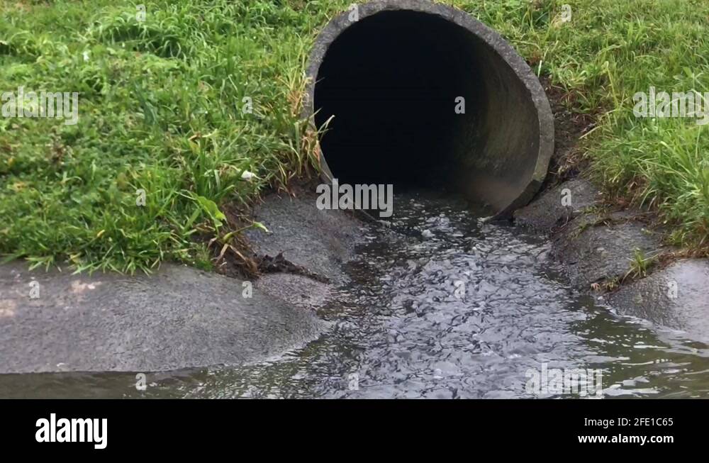 Close up view of rainwater pouring out of a storm water drain pipe into ...