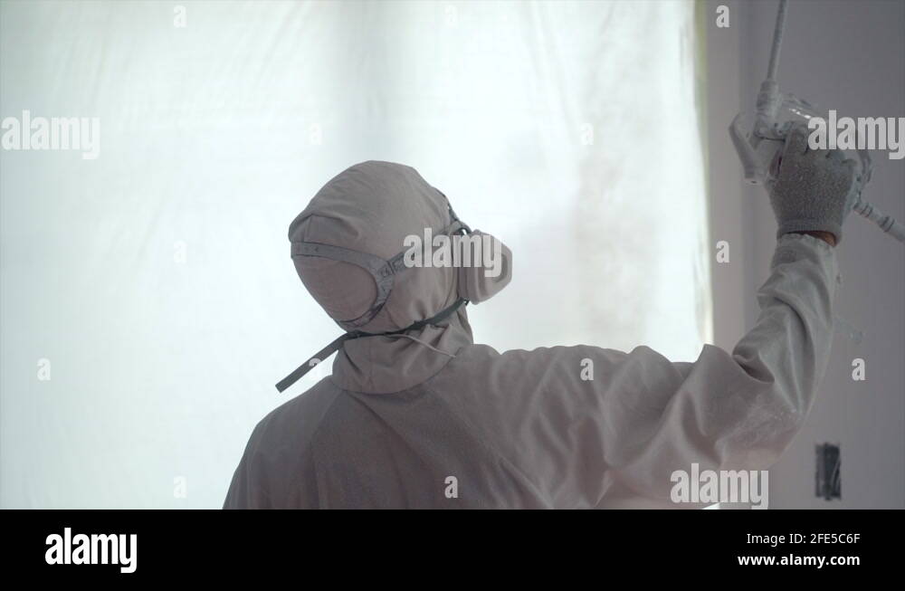 Painter Spray Painting The Ceilings And Walls Of A Newly Built House