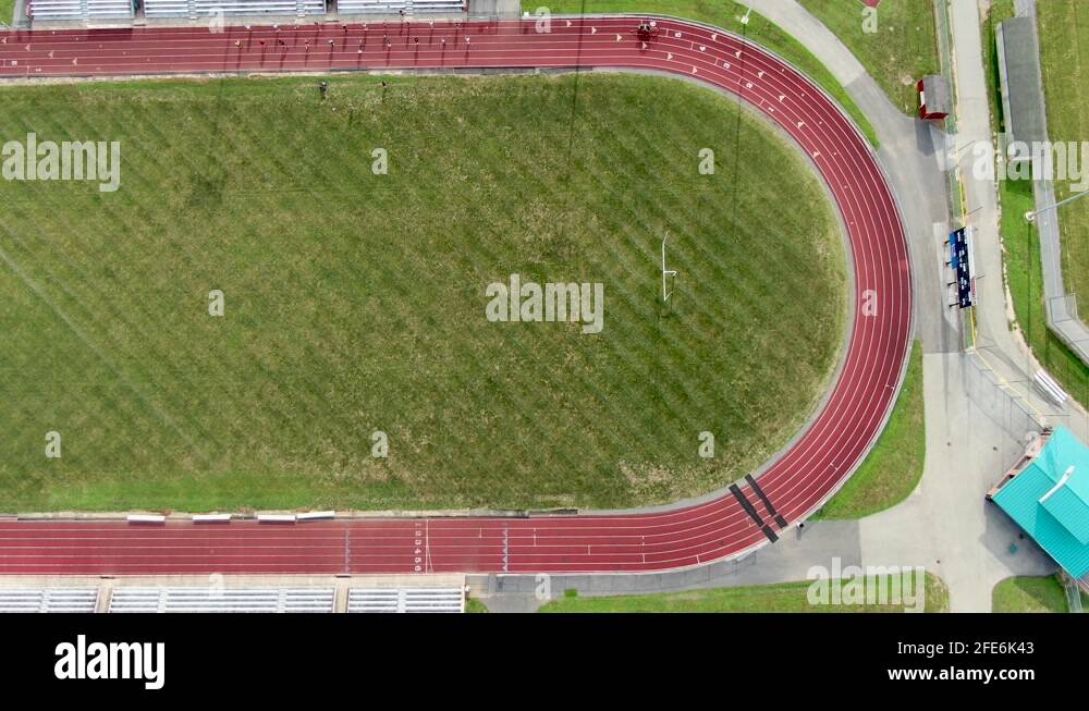 Top down aerial birds eye view of red track, green athletic field