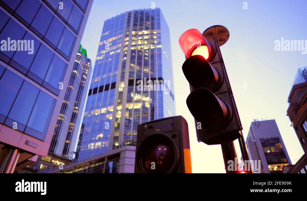 Red traffic light turning green in downtown London, at dusk with