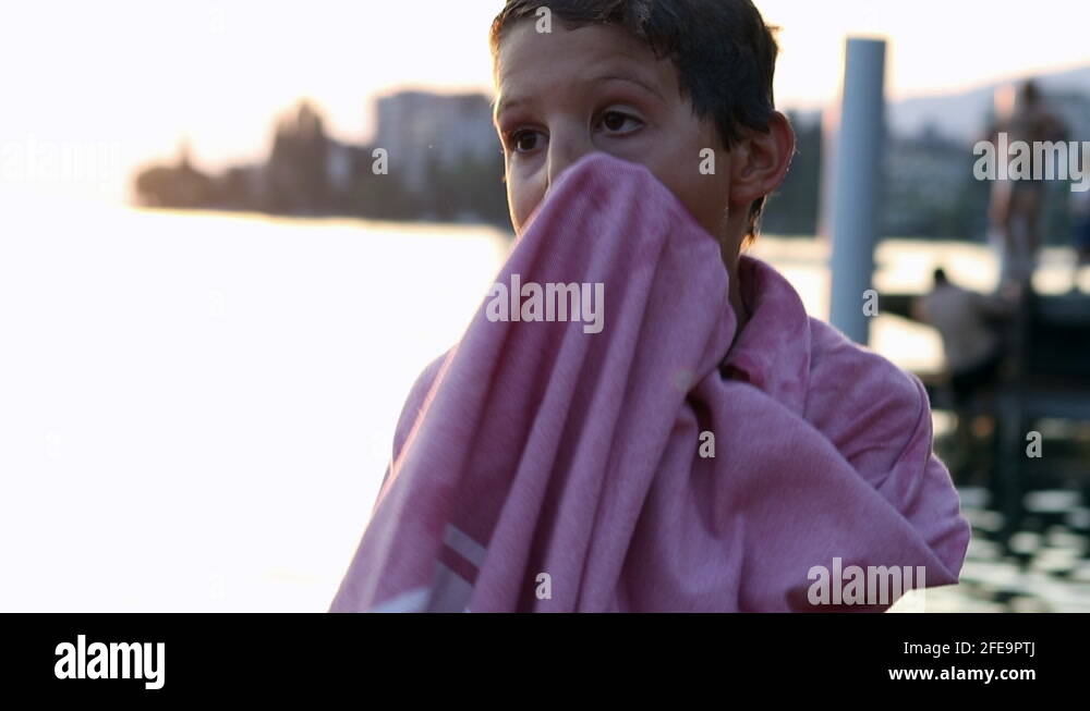Young boy drying body with towel. Child dries body after swimming at