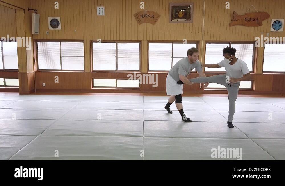 A wrestling coach demonstrates a low single leg takedown in a traditional Stock Video Footage