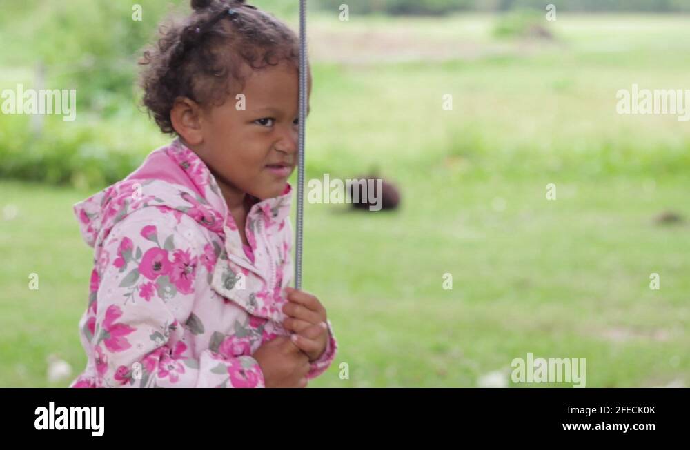 Funny little African girl making hilarious faces grabbing swing rope in