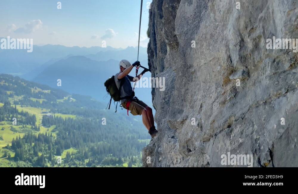 Male Hiker Walking On The Rough Boulder While Gripping On The Rope ...