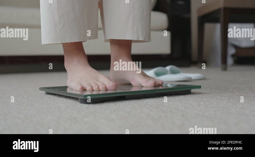 Woman stands on scale to measure her weight Stock Video Footage Alamy