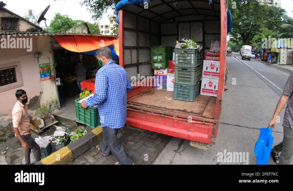 Men Unloading Crates Of Fruits And Vegetables From A Delivery Truck In