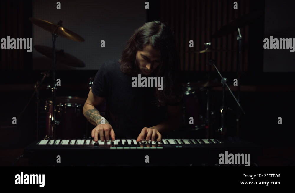 Man playing keyboard in music studio. Guy smiling in recording studio