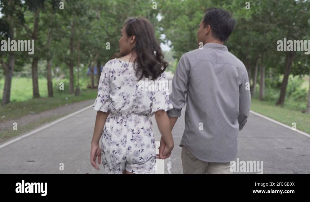 Filipino Asian Couple Holding Hands While Walking Together In A Long