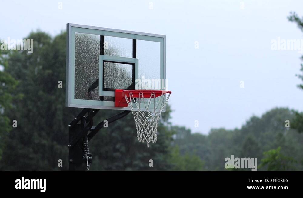 Unused outdoor basketball net with glass backboard in misty rain Stock