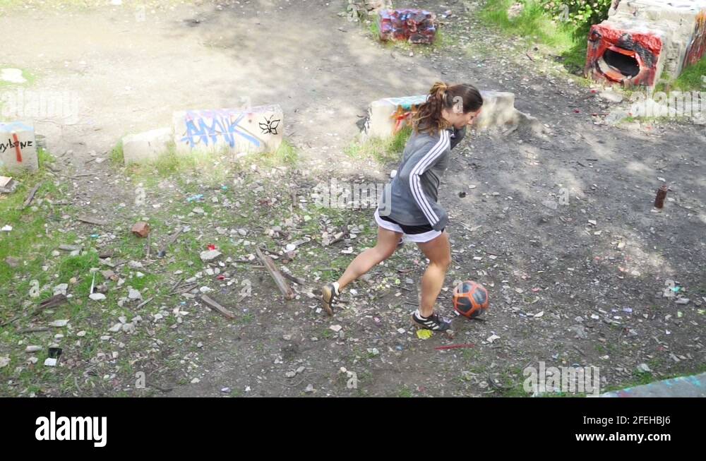 Girl dribbling soccer ball in graffiti area, athlete practicing drills