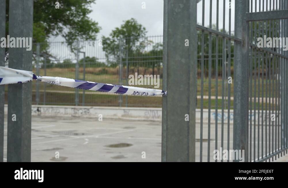 Police tape tied to fence of basketball court, panning reveal shot