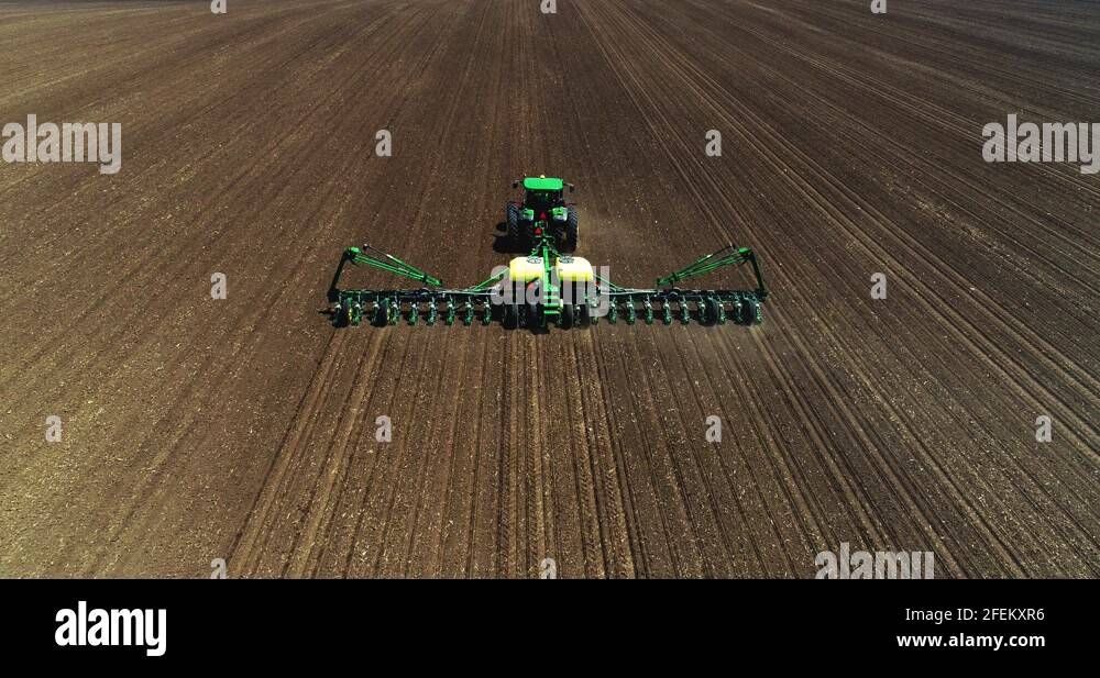 John Deere tractor and planter going across a freshly tilled field with ...