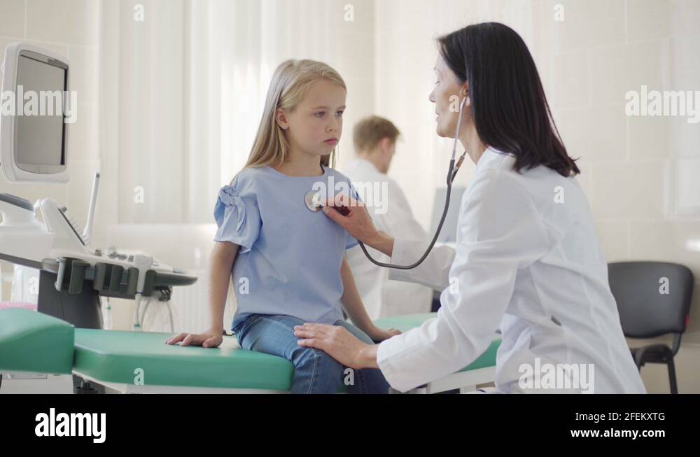 Doctor with stethoscope listening to lung sounds of little girl Stock