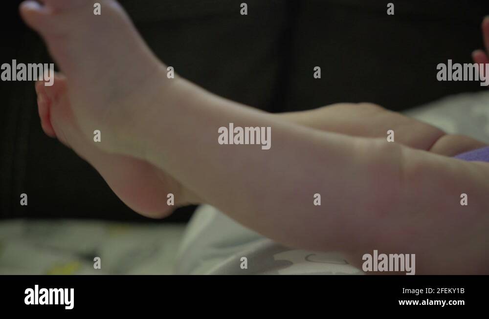 Cute growing and active baby girl kicks and stretches her legs, feet